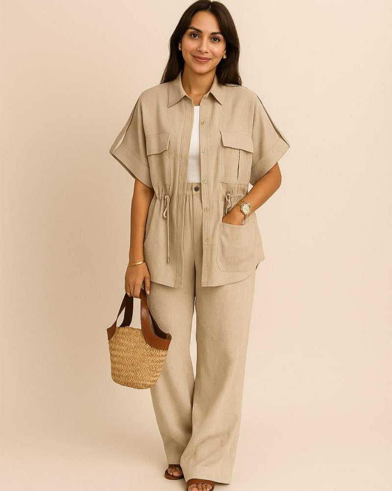 Woman wearing a beige outfit with wide-leg pants and holding a straw bag on a beige background