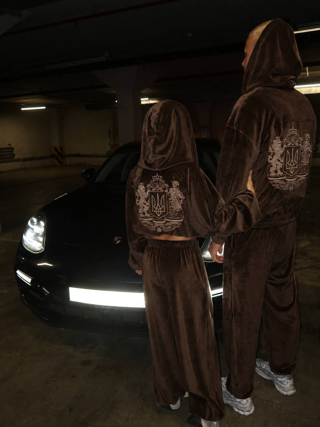 Man wearing chocolate velour tracksuit with embroidered Ukrainian coat of arms on the back