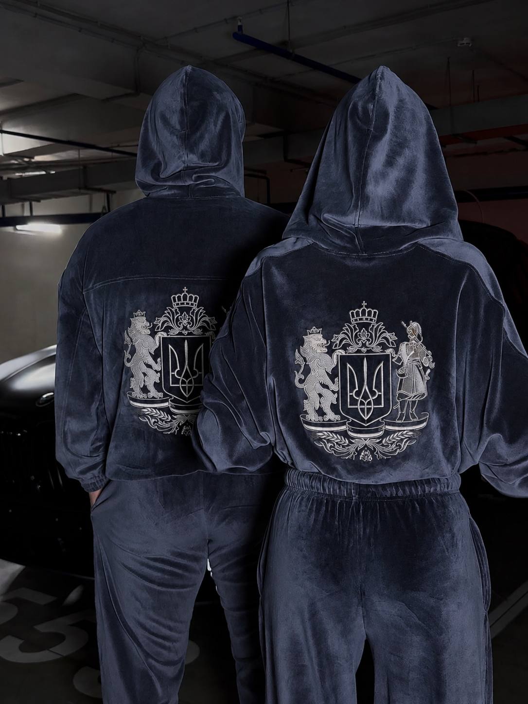 Man wearing dark navy velour tracksuit with embroidered Ukrainian coat of arms on the back