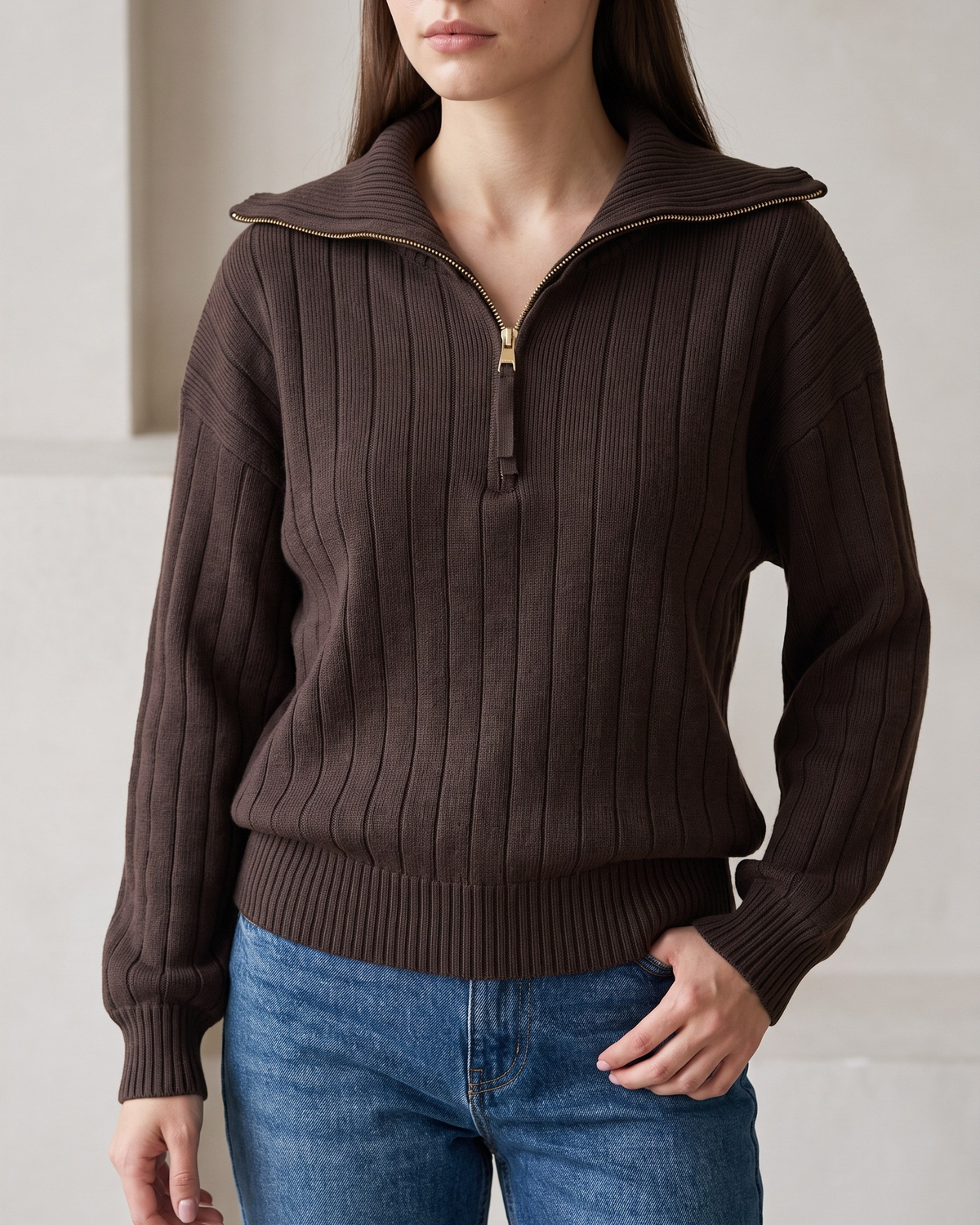 Frau in einem schokoladenbraunen Rippstrick-Sweatshirt mit Halbreißverschluss, Vorderansicht mit Jeans