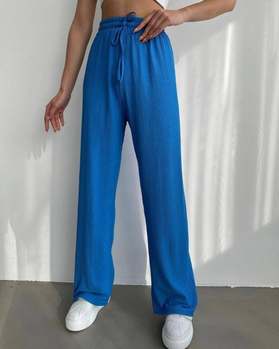Person wearing blue pants and white sneakers on a plain background