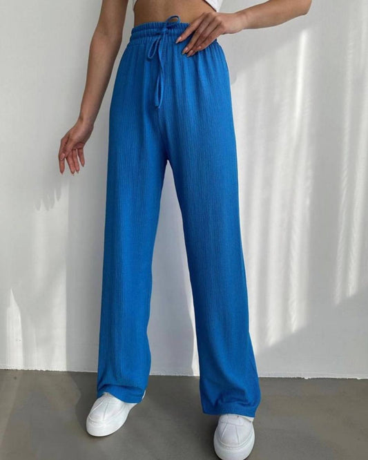 Person wearing blue pants and white sneakers on a plain background