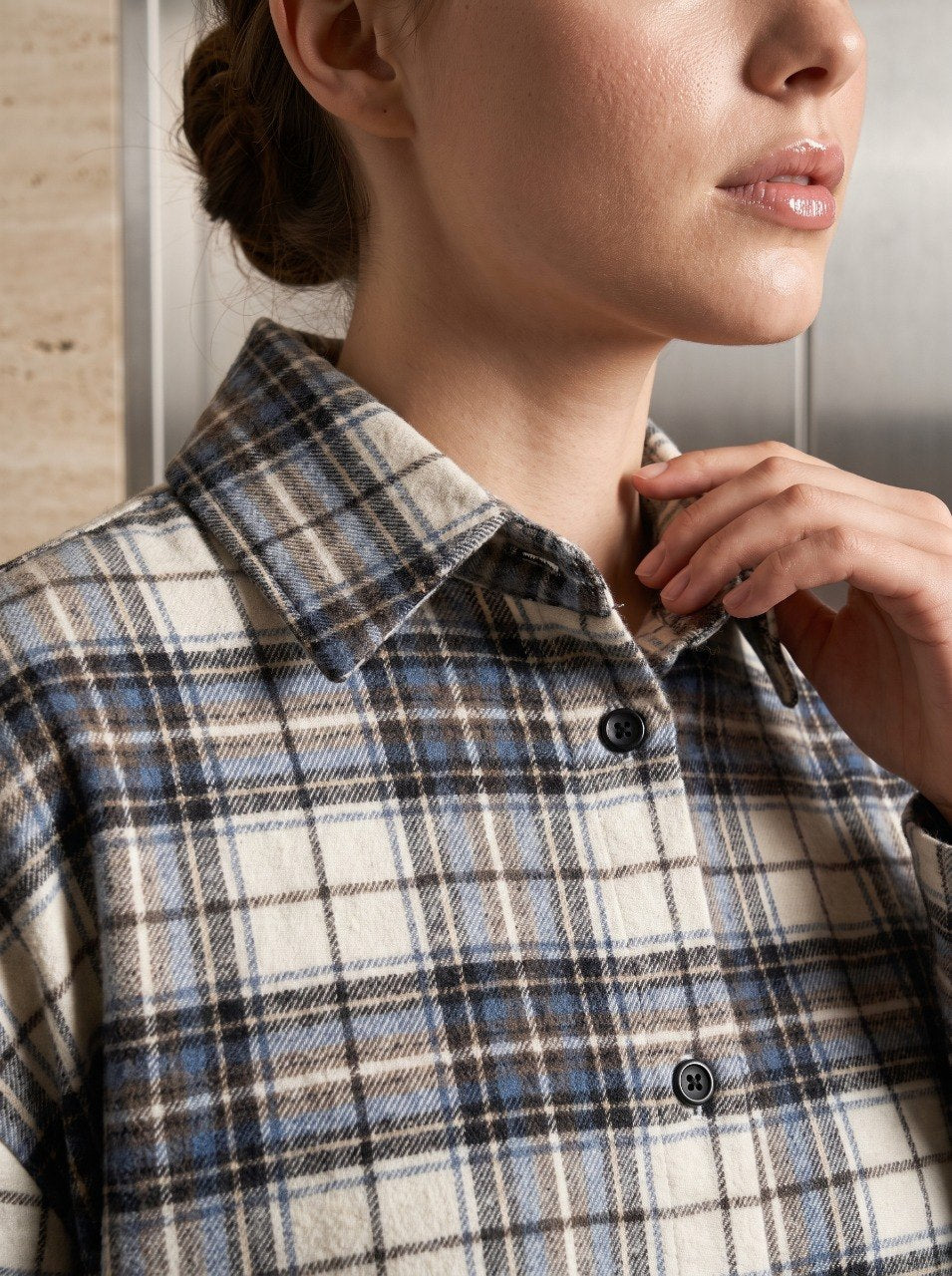 Close-up of a beige plaid flannel shirt's classic point collar and button-front closure