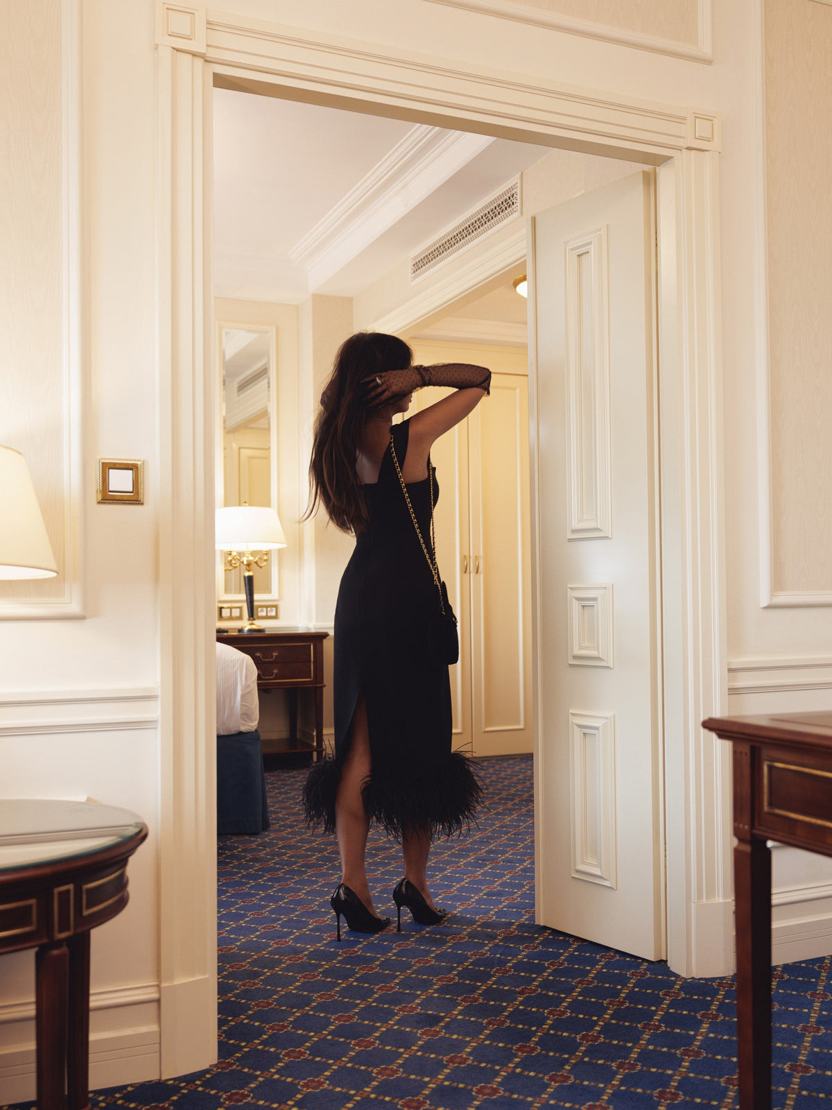Black midi dress with back zip closure – back view in doorway
