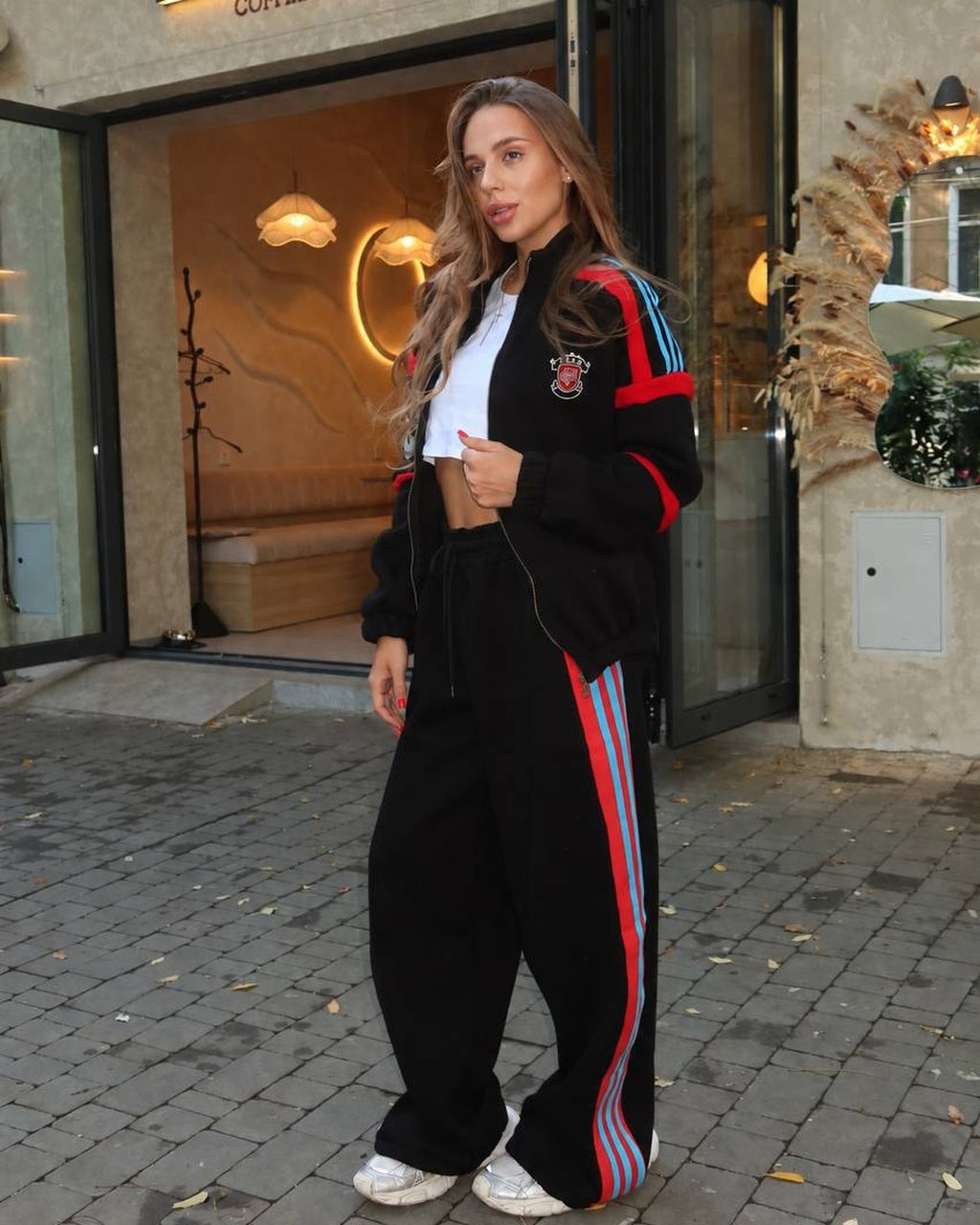 Black women's tracksuit with red and light-blue stripes, zip jacket and wide-leg trousers, front view
