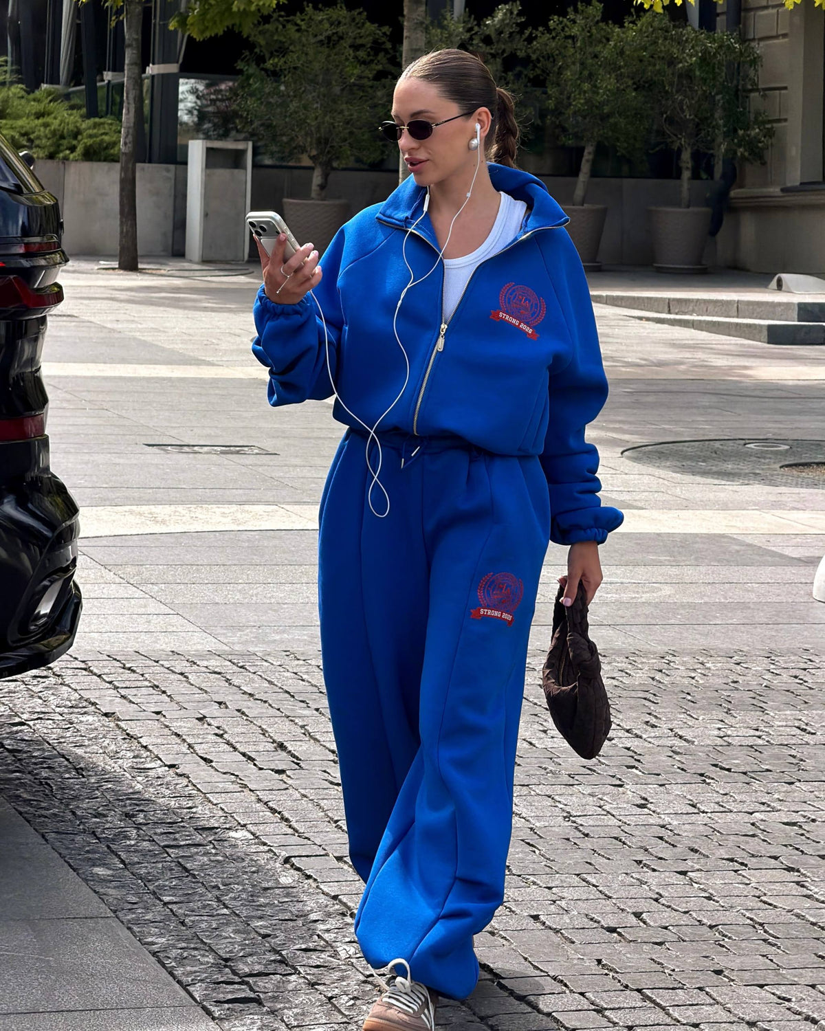 Blue fleece-lined tracksuit with red crest print - walking look with a white tank top