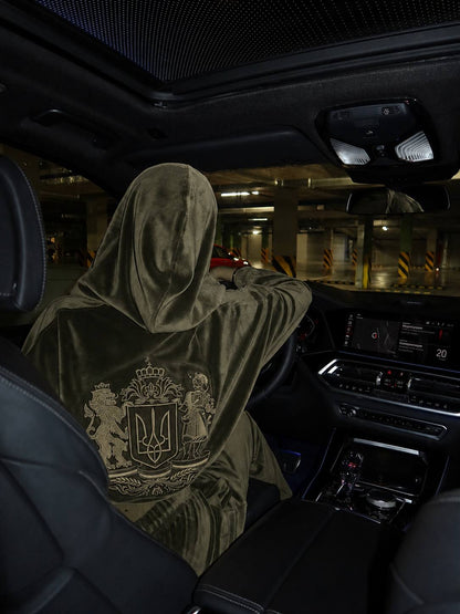Side-back view of khaki velour hooded tracksuit with embroidered Ukrainian coat of arms, woman driving car
