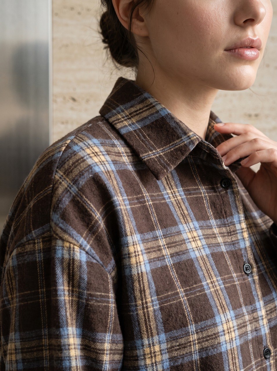 Close-up of a brown plaid flannel shirt's classic point collar and button-front closure