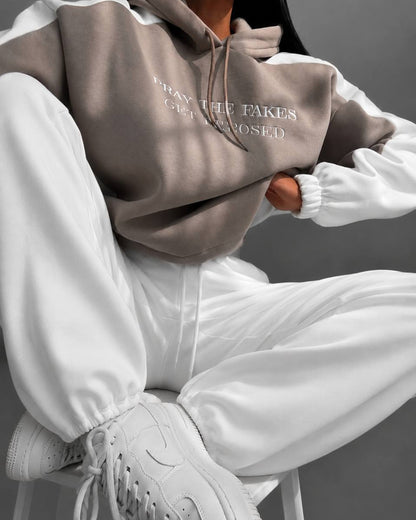 Beige hoodie with milk-white sleeves and fleece joggers - close-up seated on a stool
