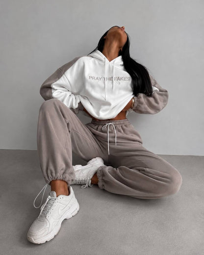 Milk-white hoodie and beige fleece joggers with elasticated cuffs - seated on the floor with chunky sneakers