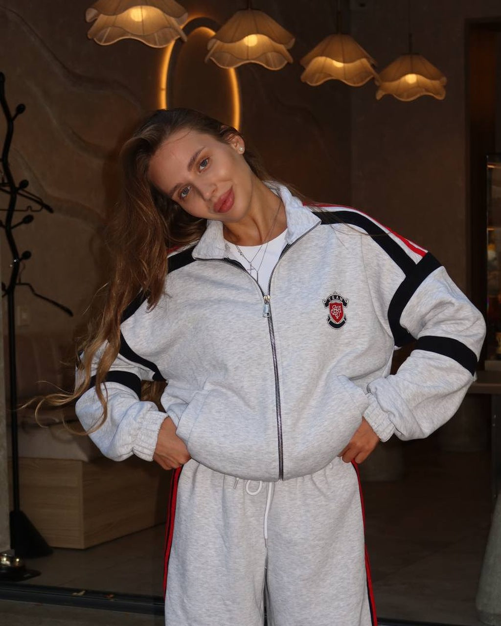 Light gray melange women's tracksuit with black panels and red stripes, zip jacket close-up