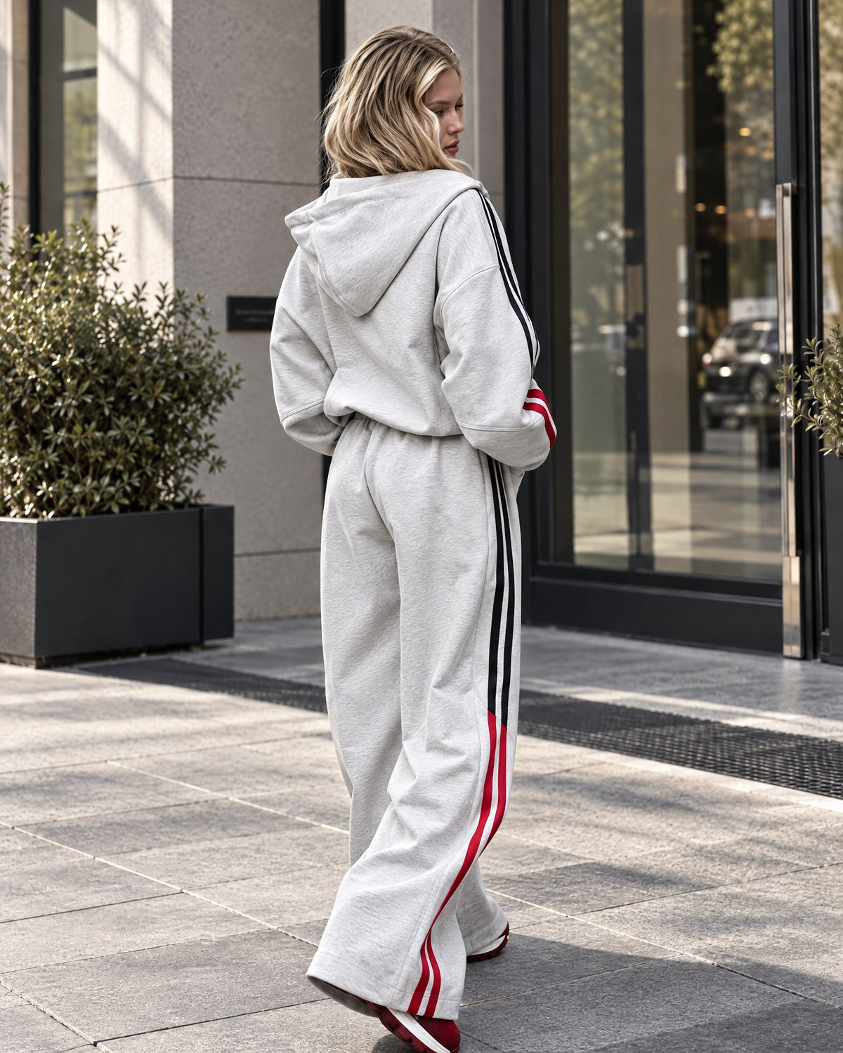 Light gray melange tracksuit with black and red side stripes - back view of hoodie and wide-leg trousers
