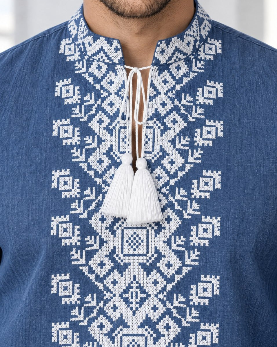 Close-up of white cross-stitch embroidery on blue linen collar and chest