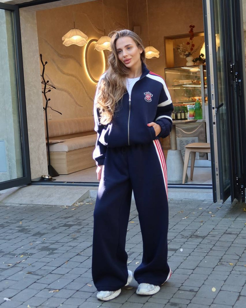 Dark blue women's tracksuit with white panels and red stripes, zip jacket and wide-leg trousers, front view