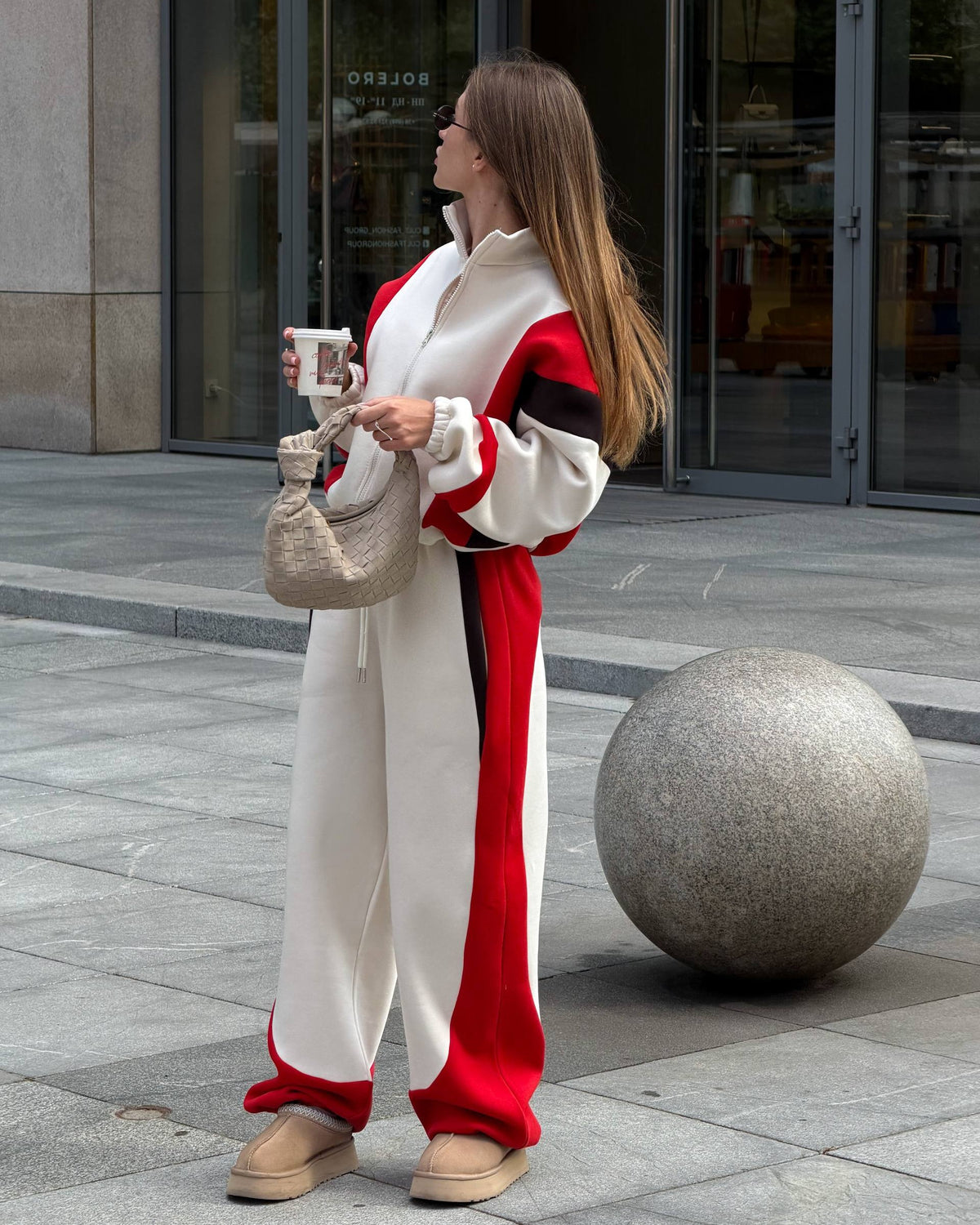 Cream zip jacket and wide-leg trousers with red side panels - full-length side view with a woven bag