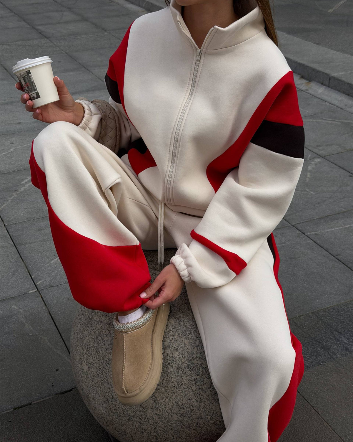 Cream fleece-lined tracksuit - seated close-up showing the zip jacket, roomy sleeves and red hem panels