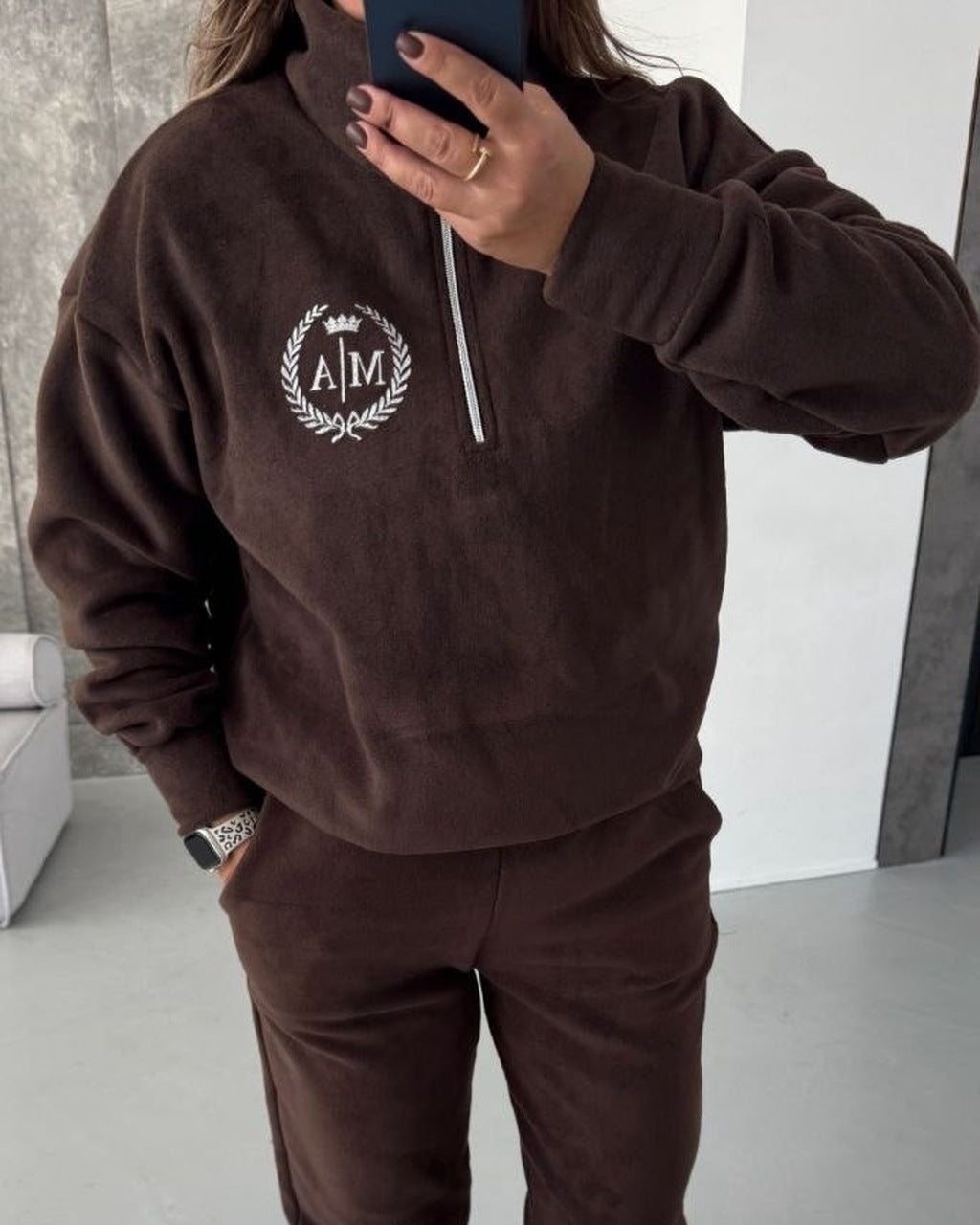Chocolate fleece half-zip sweatshirt with printed laurel wreath logo, close-up