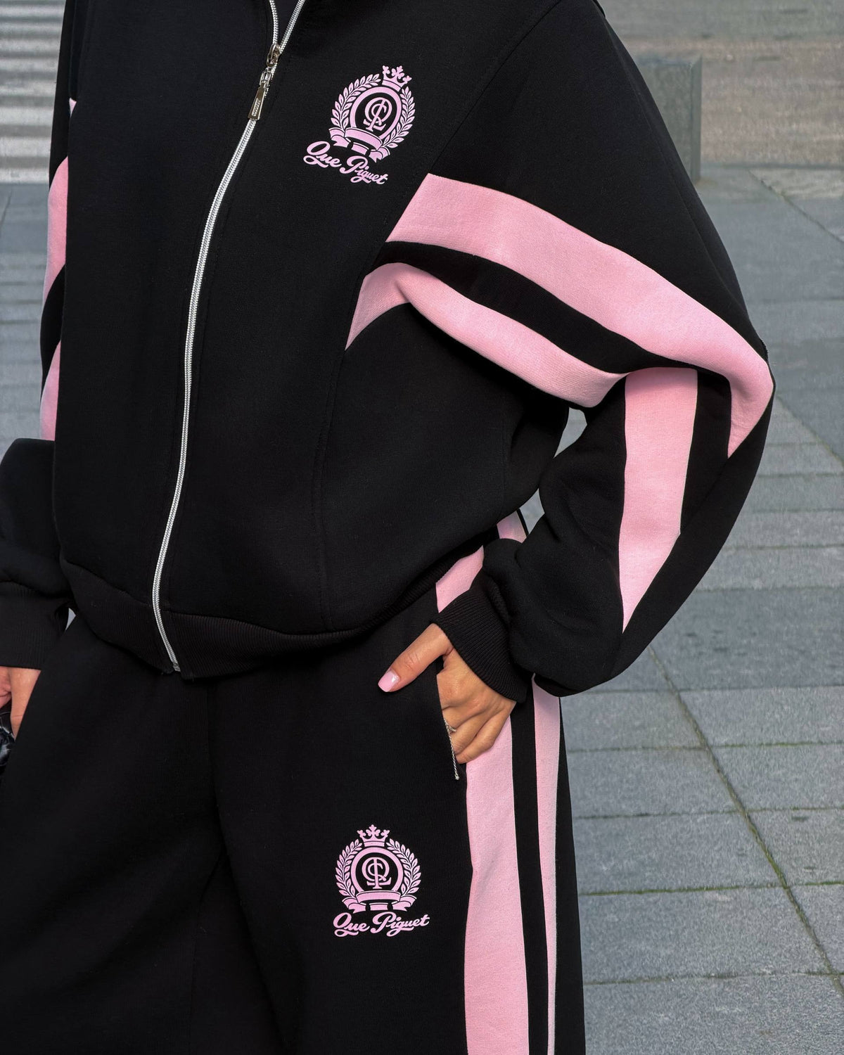 Black zip jacket with pink colour-block sleeve panels and a crest print - close-up with wide-leg trousers