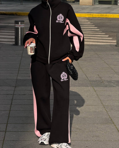 Black tracksuit with a high stand collar, silver zipper and pink sleeve panels - front view