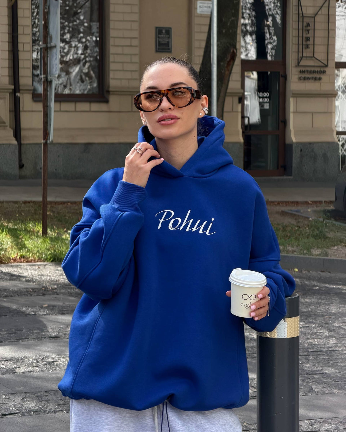 Blue fleece-lined hoodie with white embroidery on the chest - portrait with sunglasses and a coffee cup