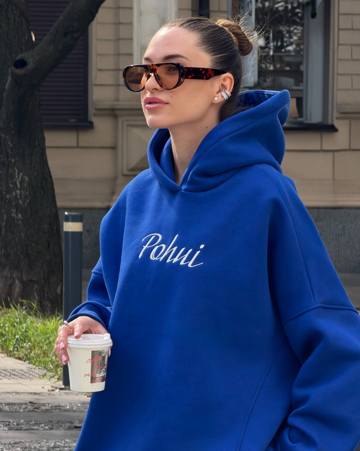 Blue oversized hoodie close-up with a roomy hood and white embroidered lettering