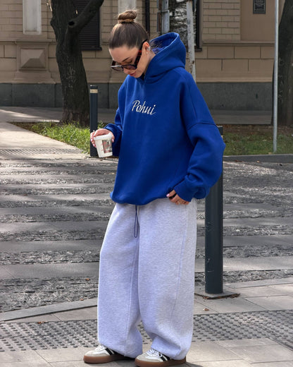 Blue oversized hoodie with dropped shoulders and ribbed cuffs - full-length view with grey wide-leg trousers