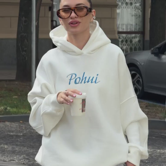 Short video of the milk-white oversized hoodie with blue embroidery worn on a city street