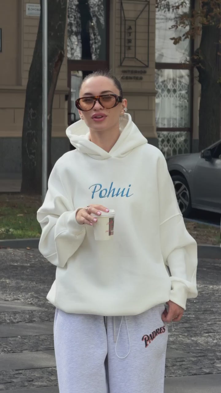 Short video of the milk-white oversized hoodie with blue embroidery worn on a city street