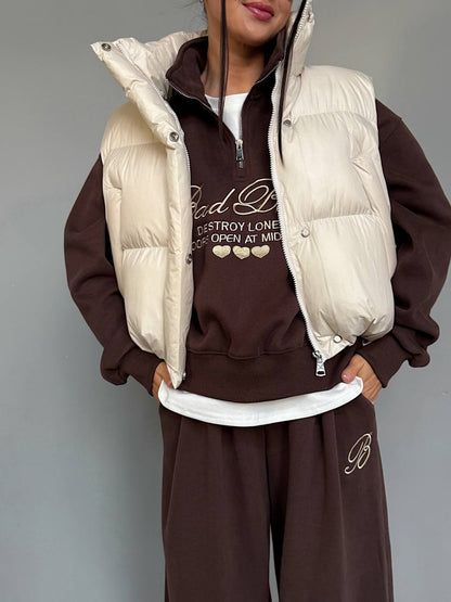 Chocolate brown embroidered fleece sweatshirt with stand collar and half zip, styled with a cream puffer vest (vest not included)