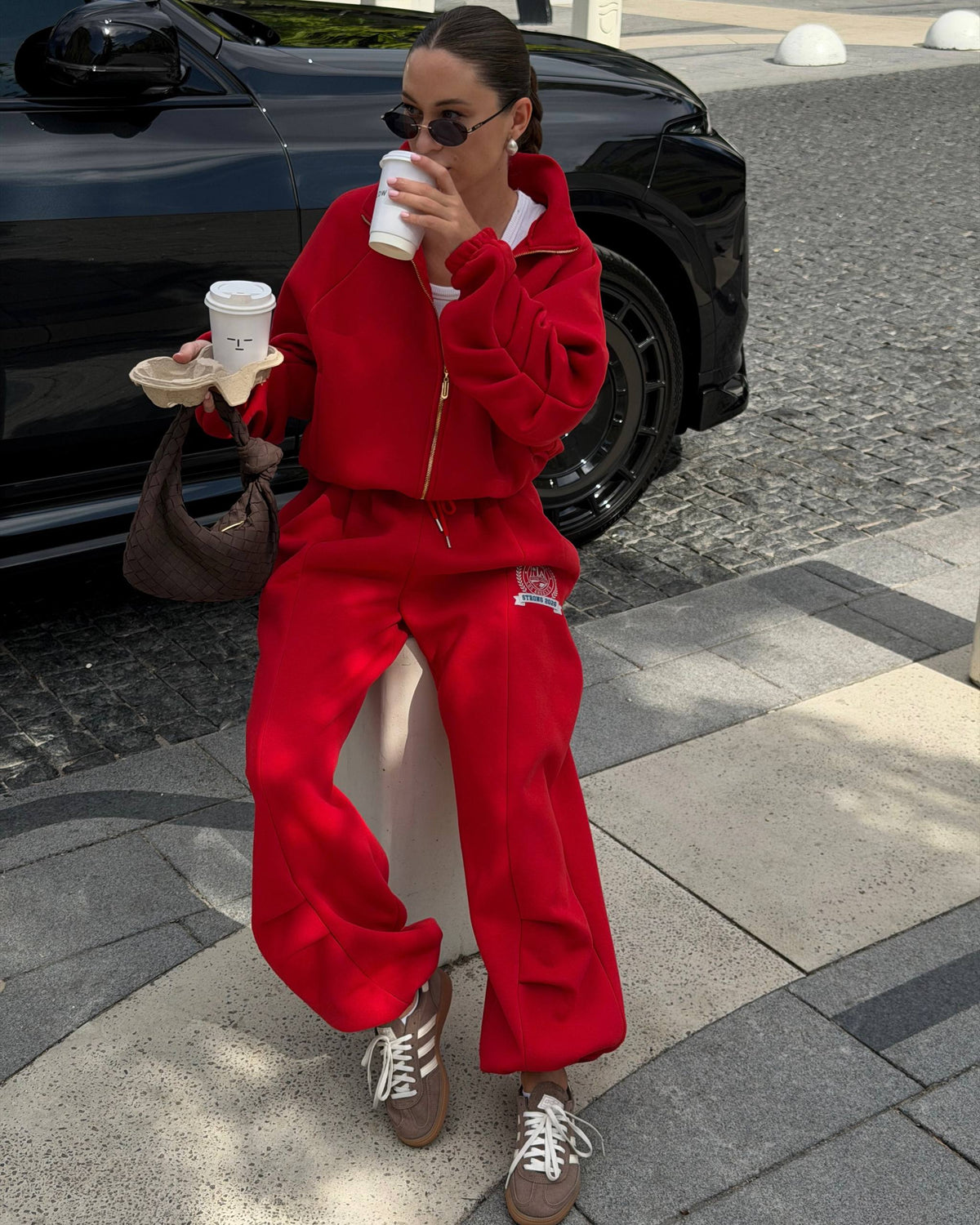 Red fleece-lined tracksuit with crest print - seated look with coffee and a brown bag