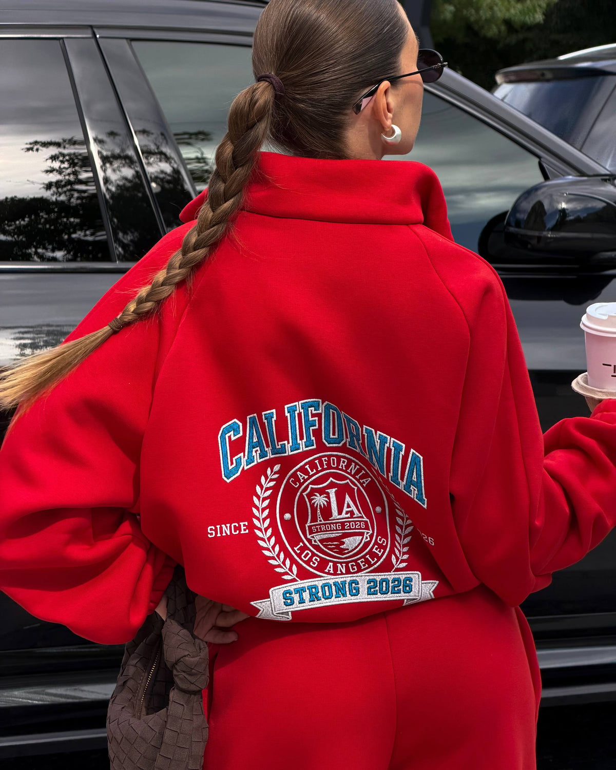 Back of a red zip jacket with a large blue and white college crest print - close-up