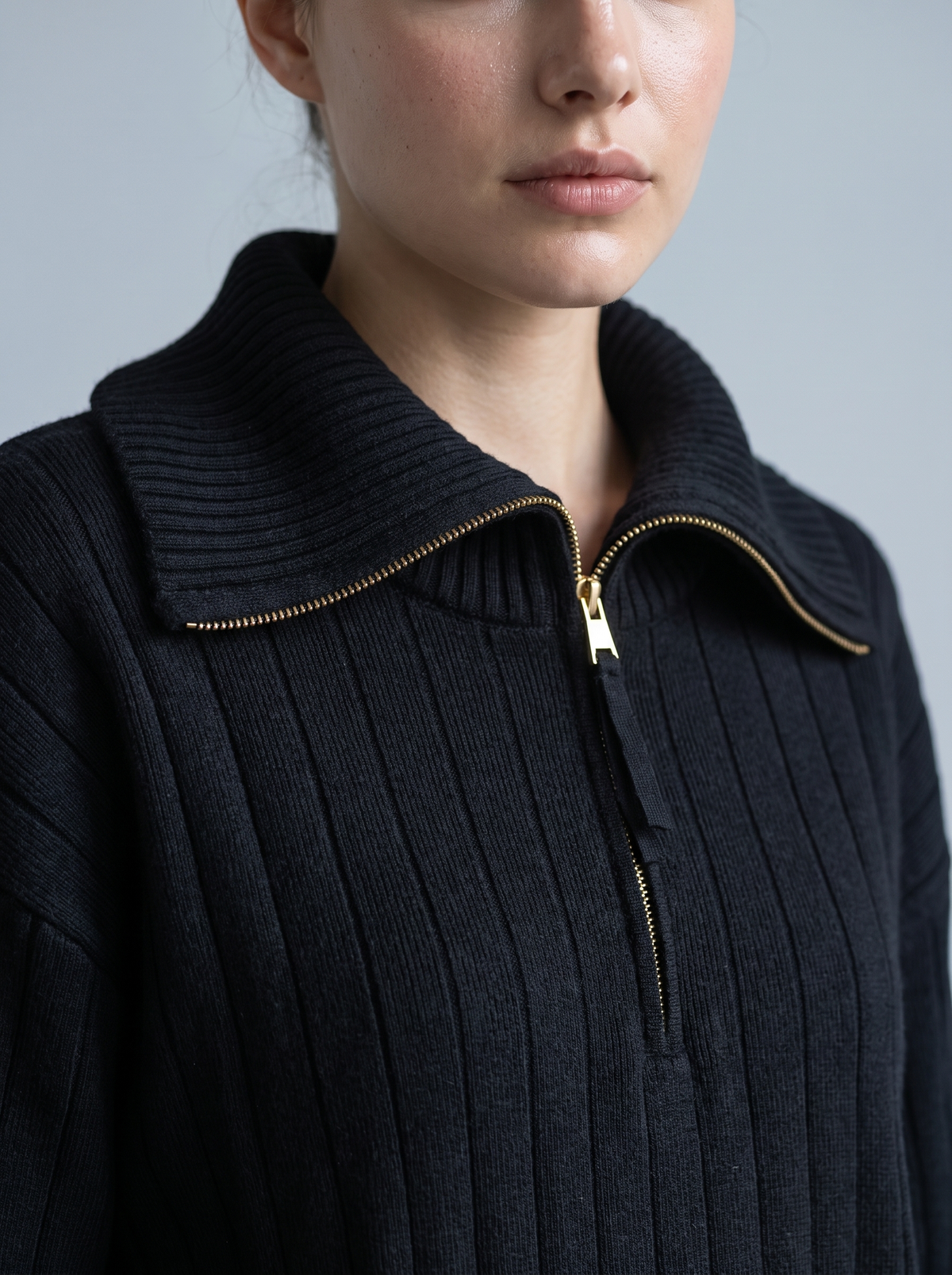 Close-up of gold half-zip pull on black ribbed knit sweatshirt collar
