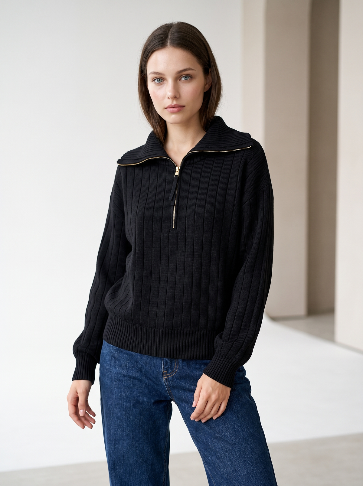 Woman wearing black ribbed knit half-zip sweatshirt with jeans, front view