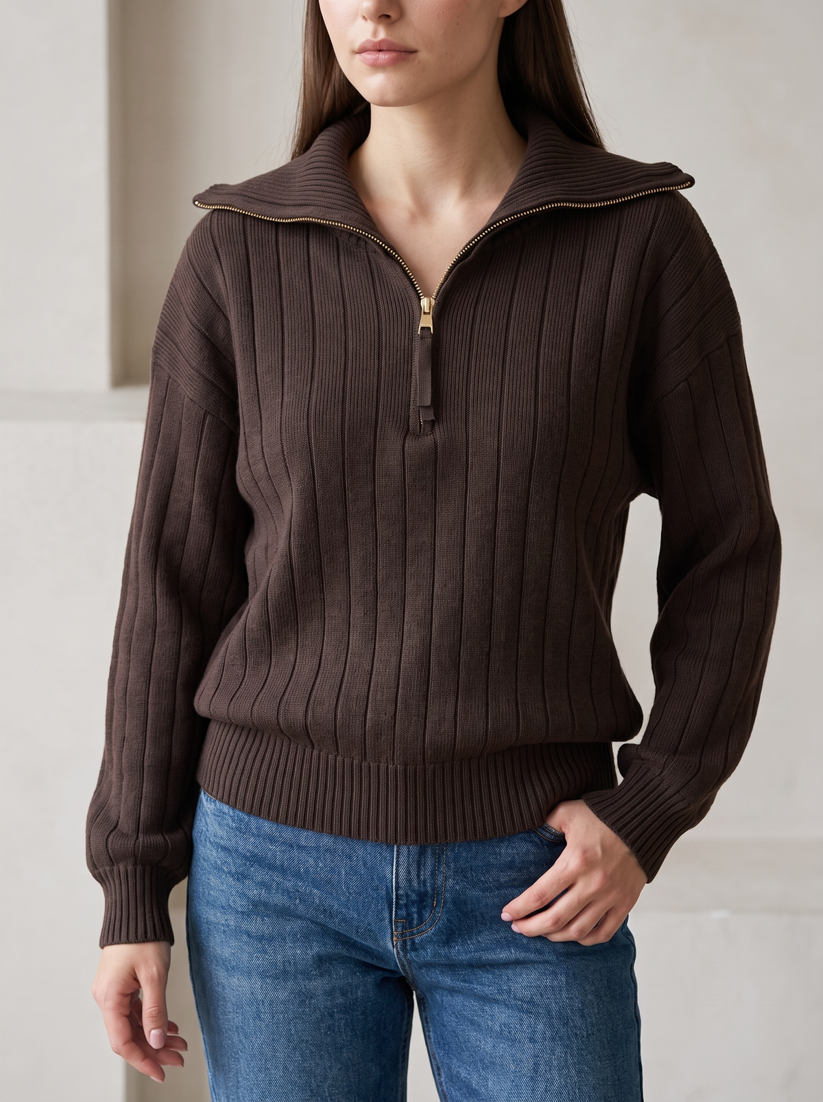 Woman wearing chocolate brown ribbed knit half-zip sweatshirt, front view with jeans