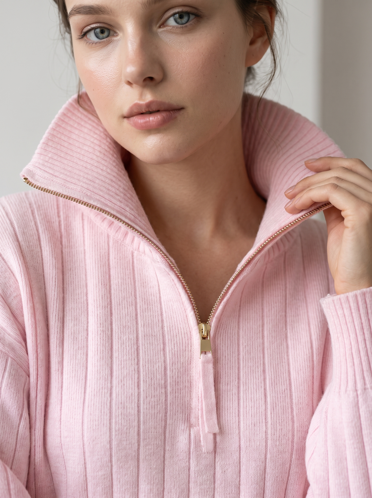 Woman wearing pink ribbed knit half-zip sweatshirt, close-up on collar and zipper